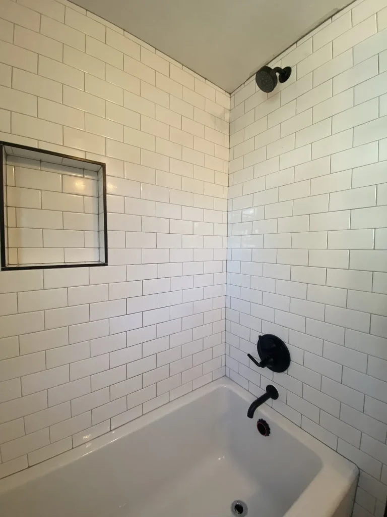 Subway tile shower with a matte black valve, shower head, and tub spout