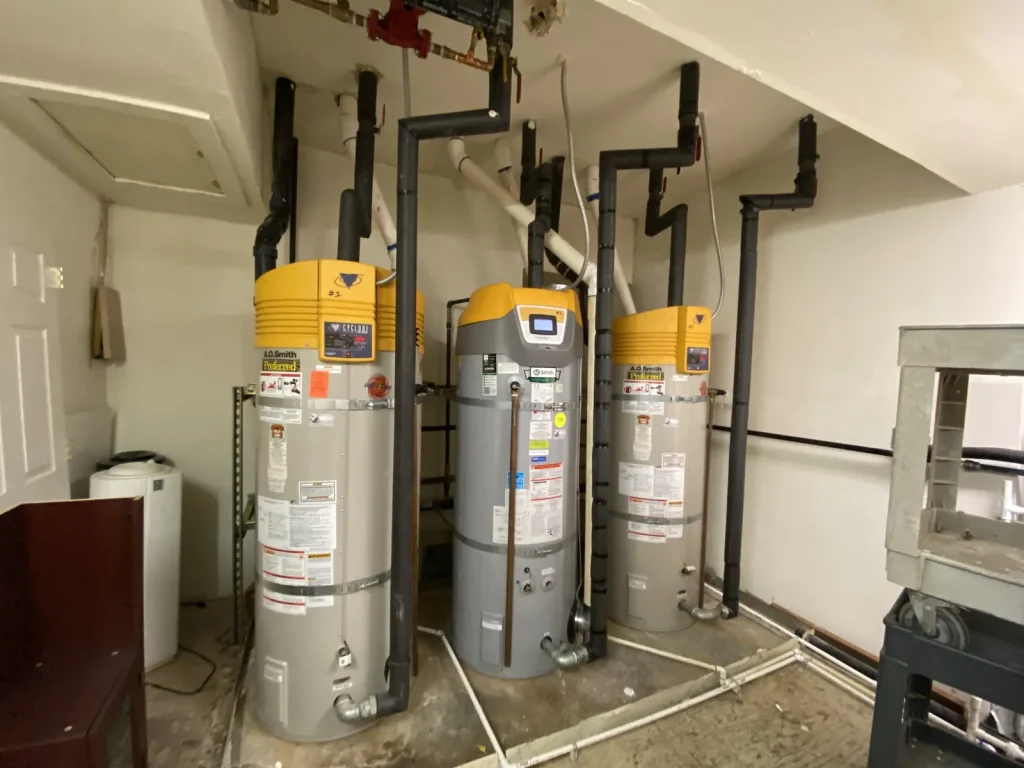 Row of power-vent water heaters installed in a mechanical room by Panda Plumbing