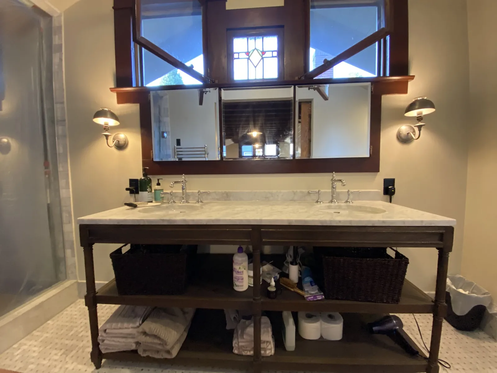 Craftsman bathroom with marble-topped open washstand, two polished column faucets, and a stained glass window