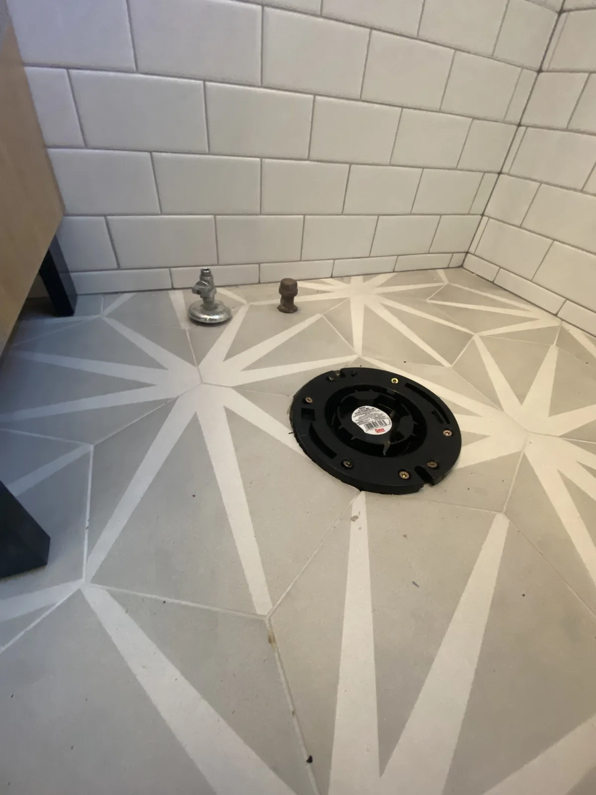 New toilet flange and chrome supply stop set flush in patterned star tile before the bowl is installed
